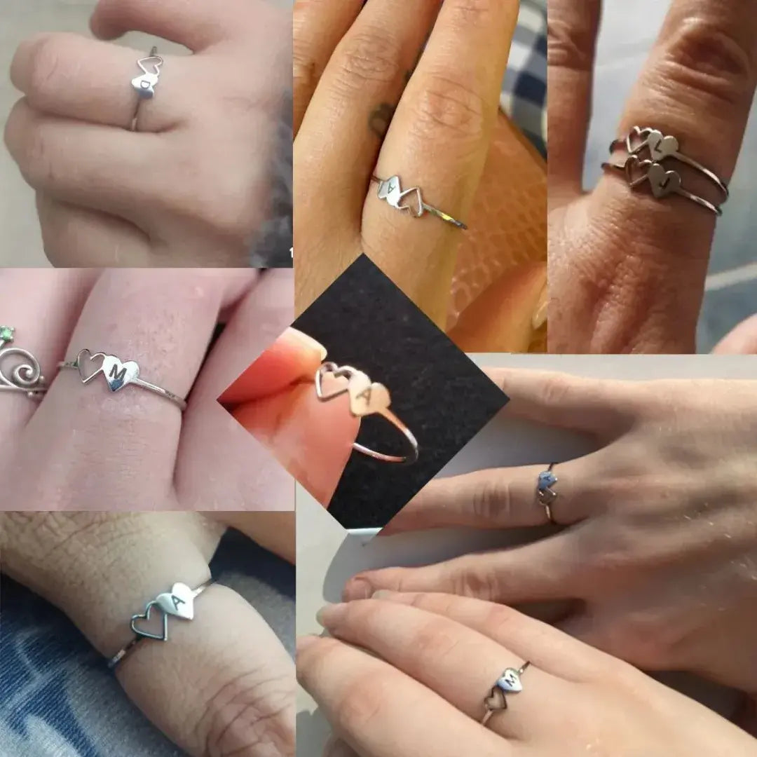 Mãos femininas exibindo diversos anéis personalizados com inicial e coração vazado – Romantizze