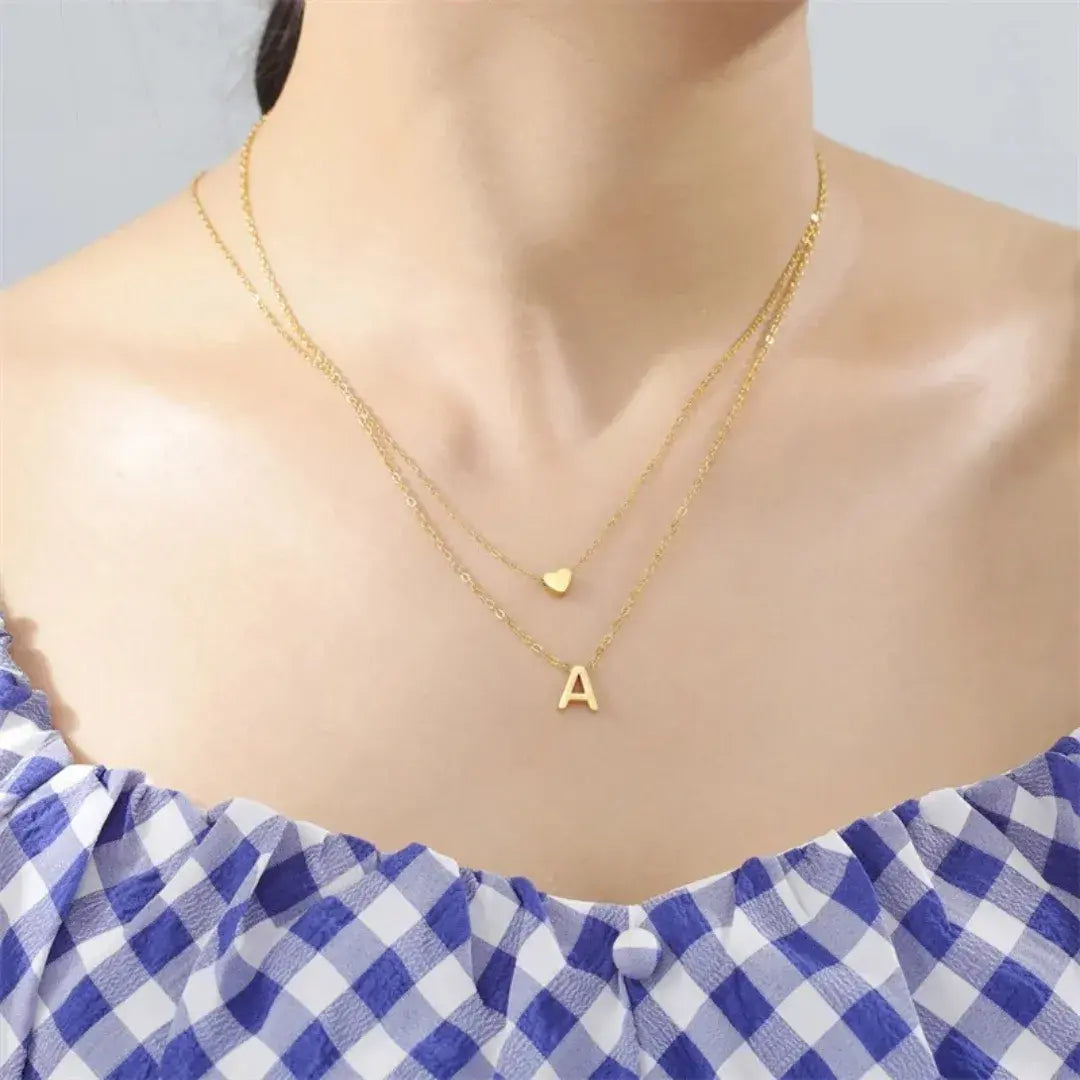 Modelo usando colar dourado da Romantizze com pingente de letra inicial e coração, estilo delicado e moderno.