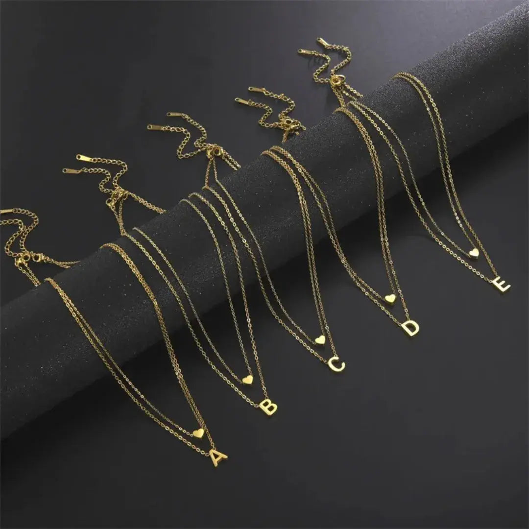 Variações do colar Romantizze com todas as letras do alfabeto em pingente dourado e prata com coração.