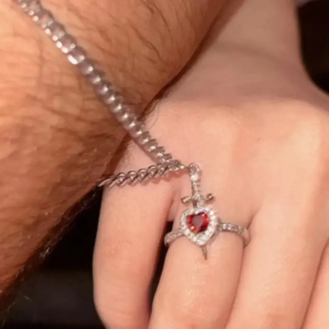 Pulseira com pingente de espada do conjunto Romantizze sendo ajustada no pulso, simbolizando proteção e romantismo.