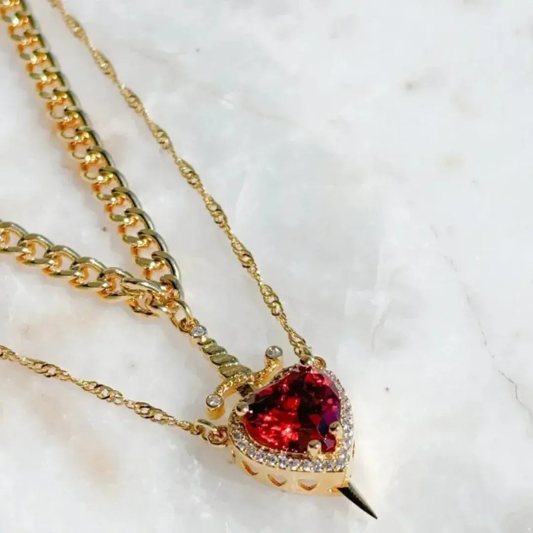 Colar dourado com pingente de coração vermelho atravessado por espada, dupla corrente – Romantizze