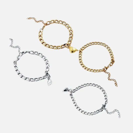 Pulseiras magnéticas Romantizze com pingente de coração para casal em aço inoxidável, nas cores dourado e prata, sobre fundo branco.